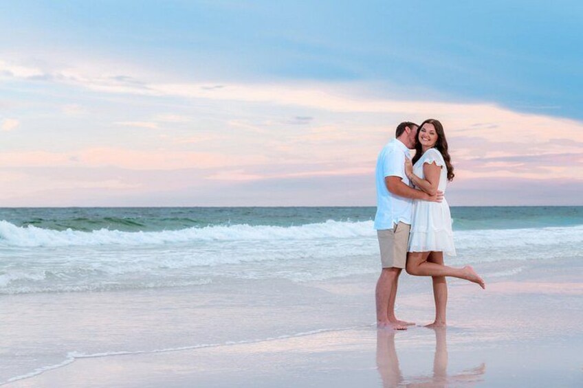 A couple embracing on a beach with waves in the background. 2