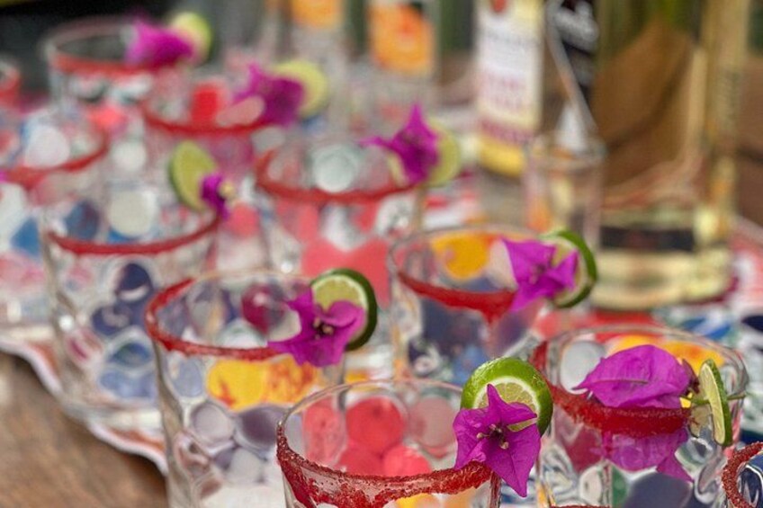 Una fila di colorati cocktail guarniti con lime e fiori. 3