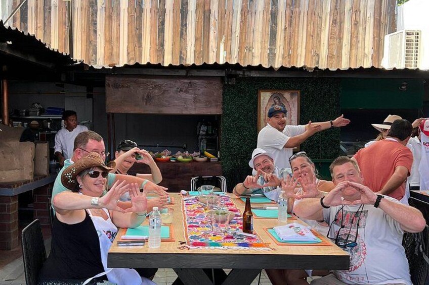 Un gruppo di persone attorno a un tavolo con diversi oggetti, probabilmente per un'attività artigianale o culinaria. 2