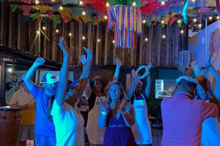 Un gruppo di persone balla in un ambiente rustico con pareti in legno e decorazioni colorate. 4