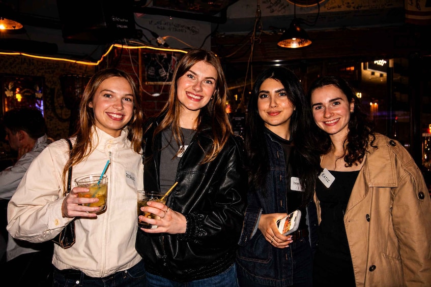Four people standing indoors, holding drinks. 3