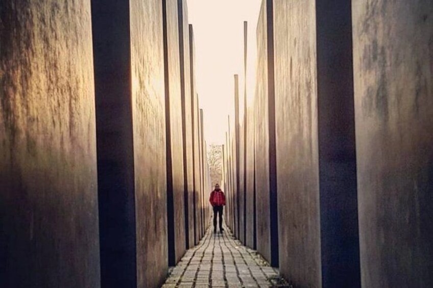 A person walking down a pathway flanked by tall, narrow columns. 1