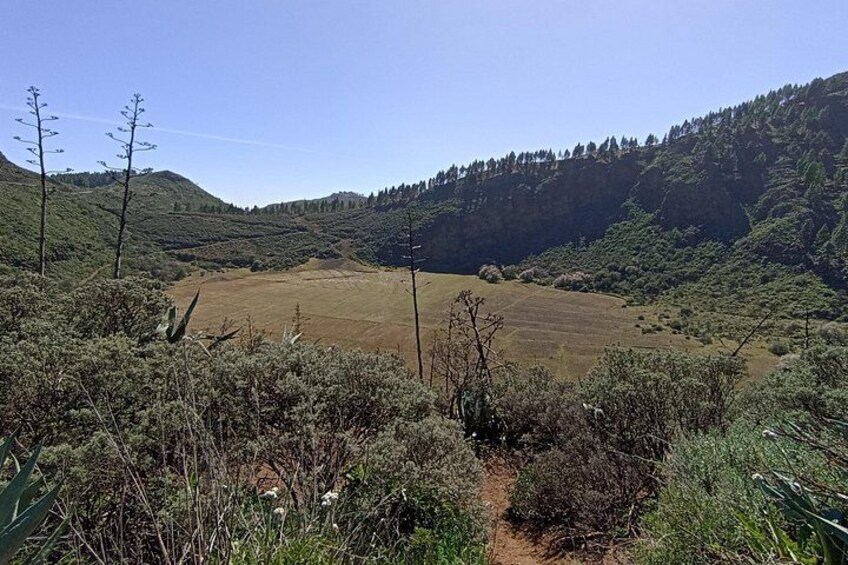 A hilly landscape with a dirt path, sparse vegetation, and a clear sky. 2