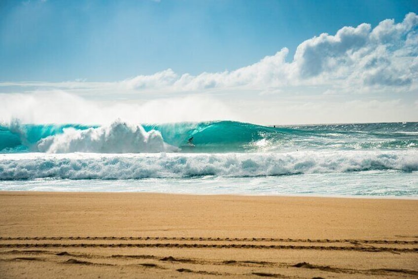 A beach with waves and a surfer. 4