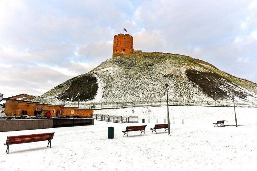 A snow-covered hill with a tower, benches, and a fence. 3