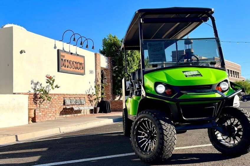 A green golf cart parked in front of a building with a sign that reads "Mission." 5