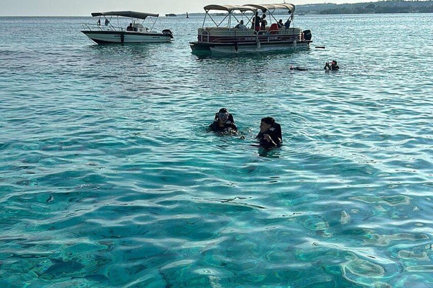 Two boats on calm turquoise water, with people swimming and snorkeling. 5