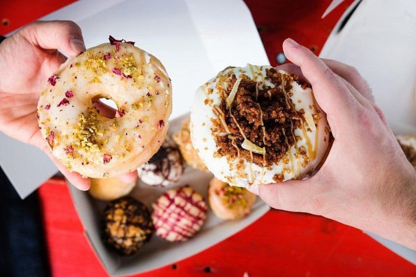 En person holder to donuts, den ene med hvid glasur og den anden med brune toppings. 1