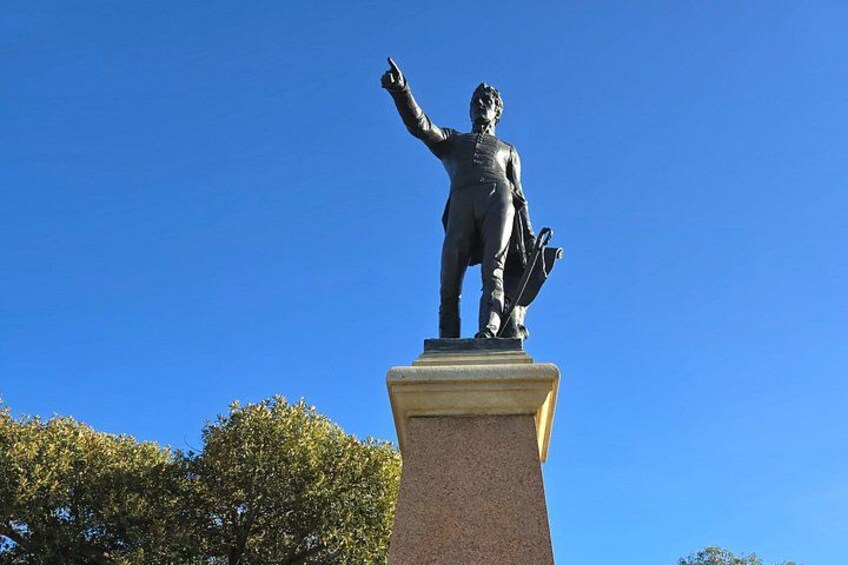 A statue of a man on a pedestal with a clear blue sky in the background. 4