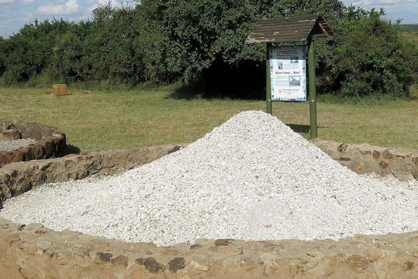A gravel pile with a signboard in a grassy field. 4