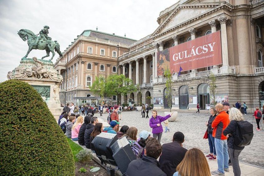 Un bâtiment historique sur lequel on peut voir une statue d’un homme à cheval, une foule de personnes et une enseigne sur laquelle on peut lire « GULÁCSY ». 3