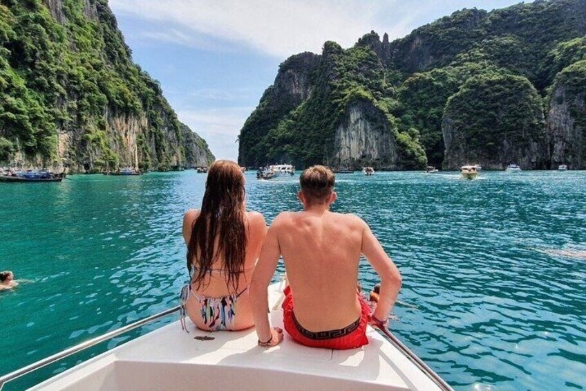 A boat with two people on a turquoise sea, surrounded by green cliffs. 4