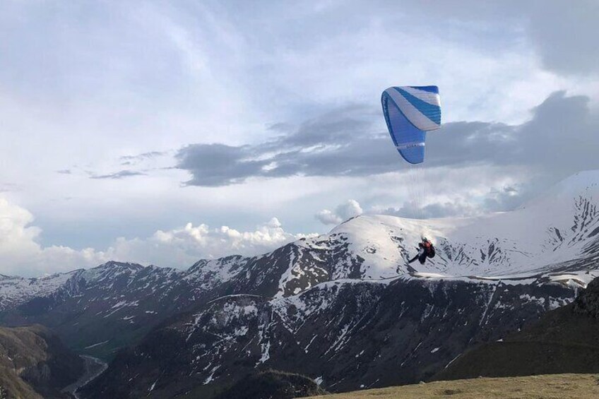 A person paragliding over a snow-covered mountain range. 5