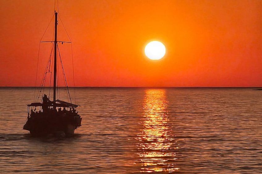 A boat on calm water during sunset with a vibrant orange sky. 3
