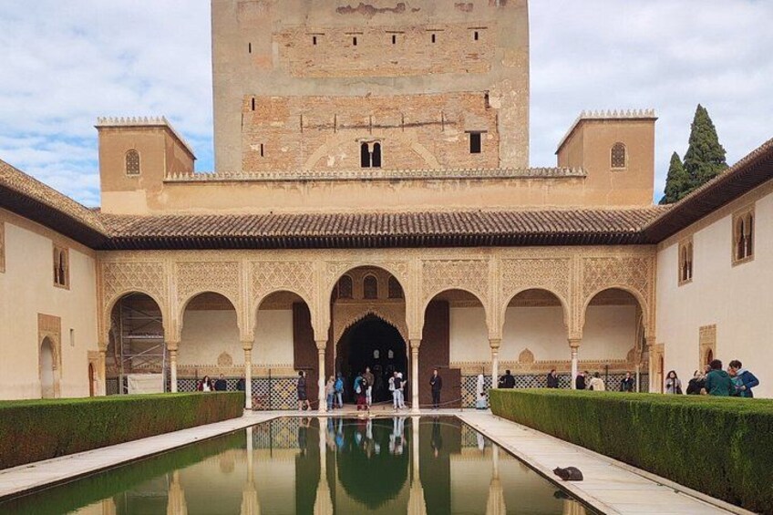 A courtyard with a pool, arches, and a tower. 3
