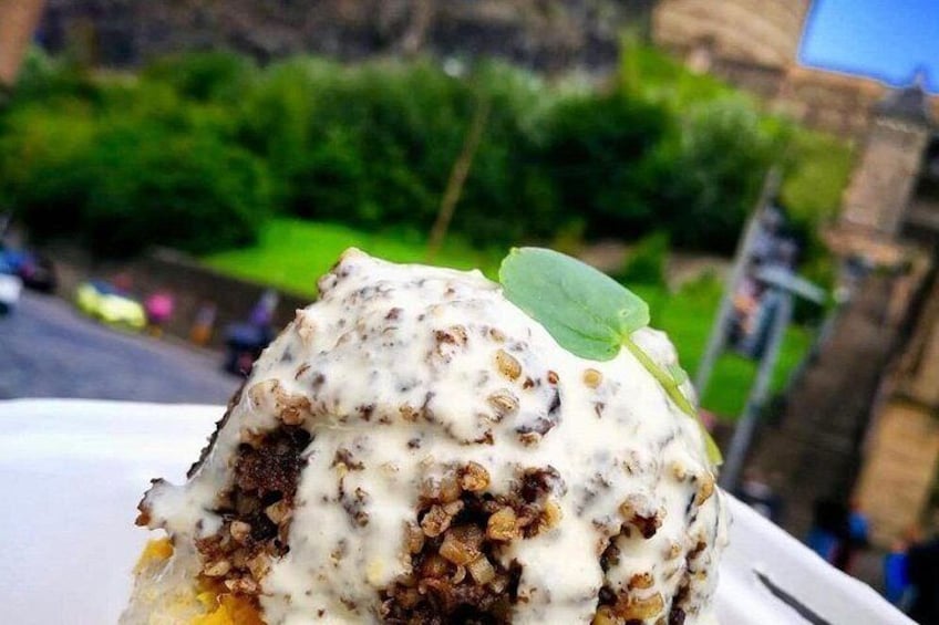 A dessert with a creamy topping, a leaf garnish, and a blurred outdoor background. 1