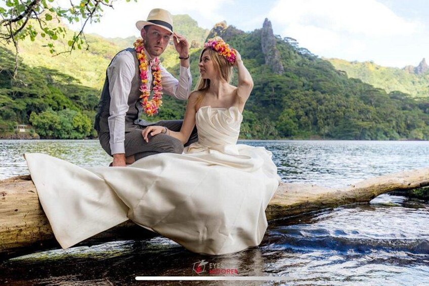 A couple sitting on a log by a lake with a mountainous backdrop. 3