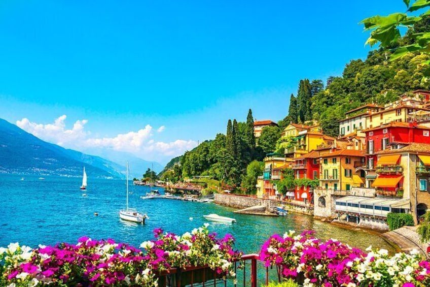 A coastal town with colorful buildings, boats on the water, and lush greenery. 1