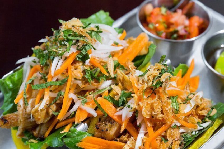 A dish with shredded carrots, herbs, and possibly chicken on lettuce. 5