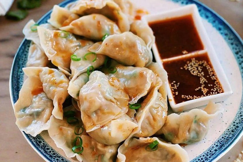 A plate of dumplings with a dipping sauce. 4