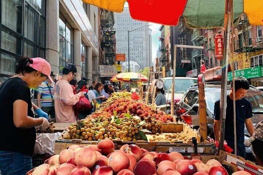 A street market with fruit stands and people shopping. 4