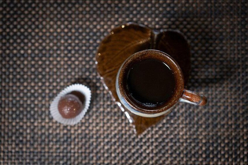Une tasse de café posée sur une surface texturée, avec un objet en forme de cœur à côté. 2