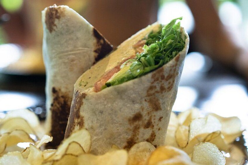 Un burrito garni de laitue et de tomates, accompagné de chips. 3