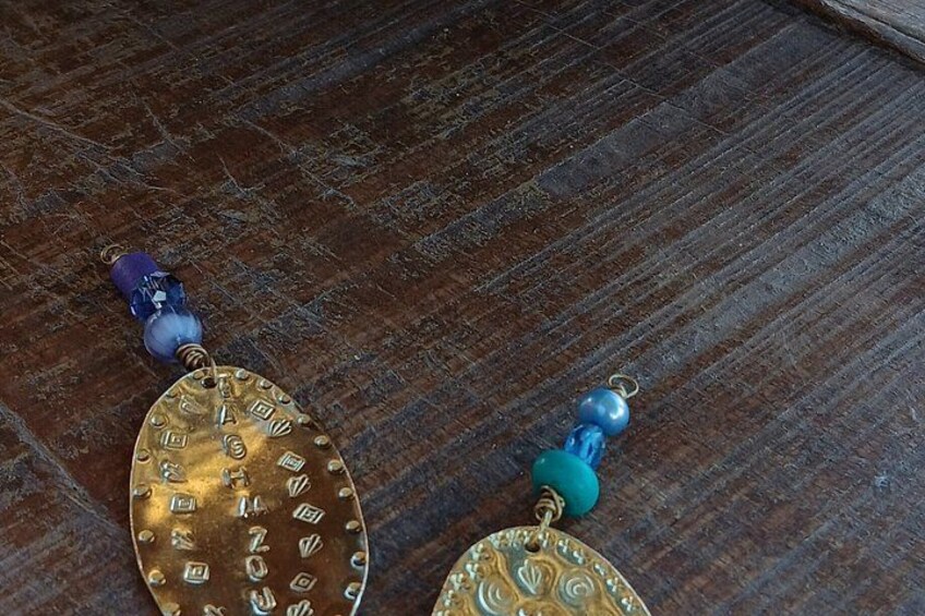 Two pendants with intricate designs, one with a blue bead and the other with a turquoise bead. 2