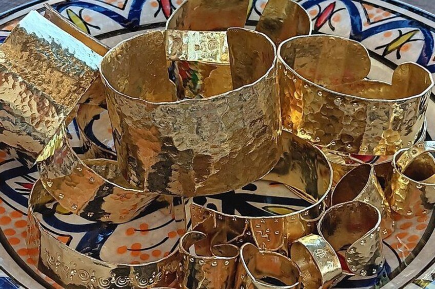 A collection of gold-colored, textured drinking vessels on a patterned surface. 3