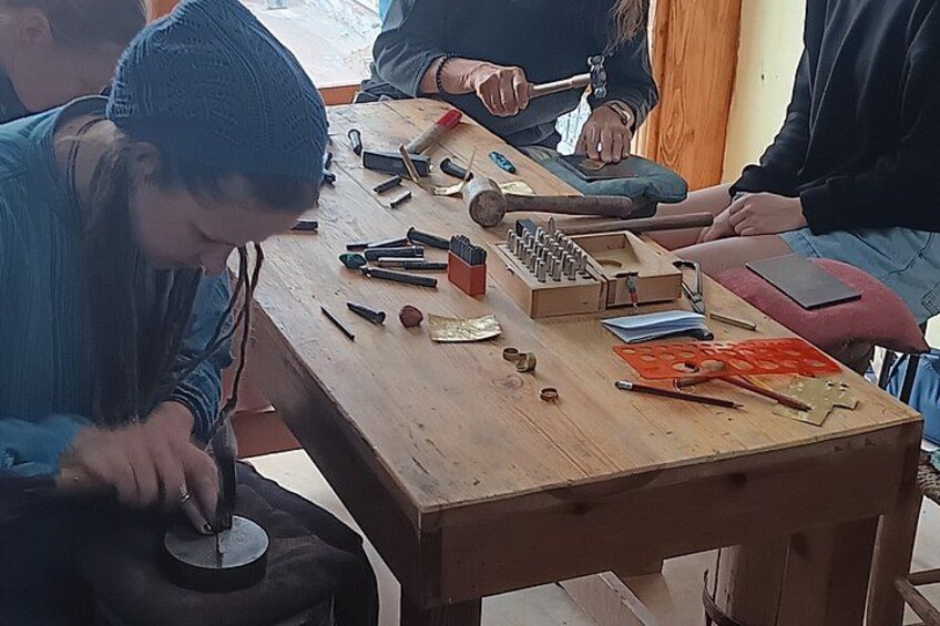 A person working with a tool on a wooden table, surrounded by various other tools and objects. 4