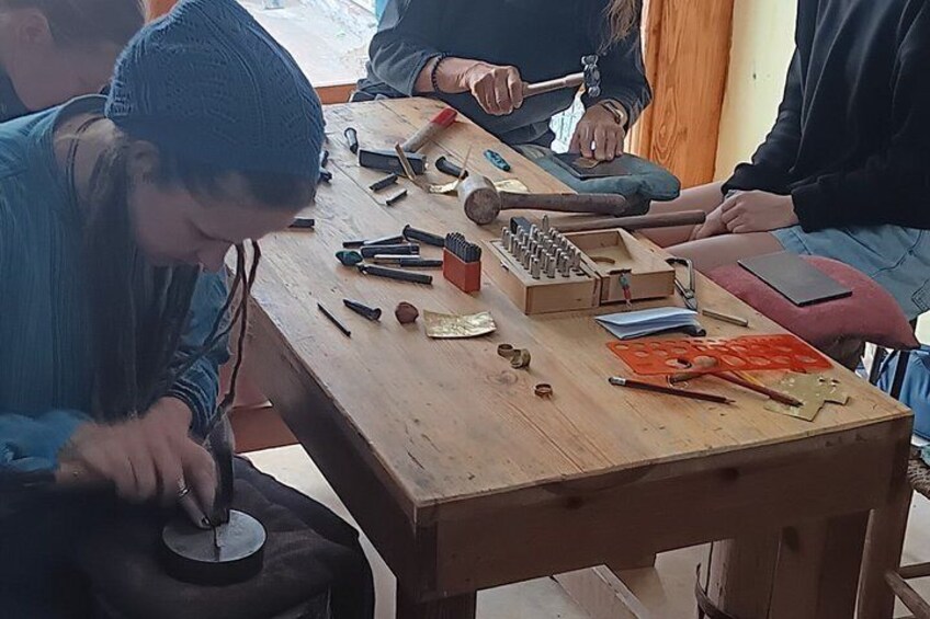 A person using a tool on a wooden workbench with various other tools and a red object. 4