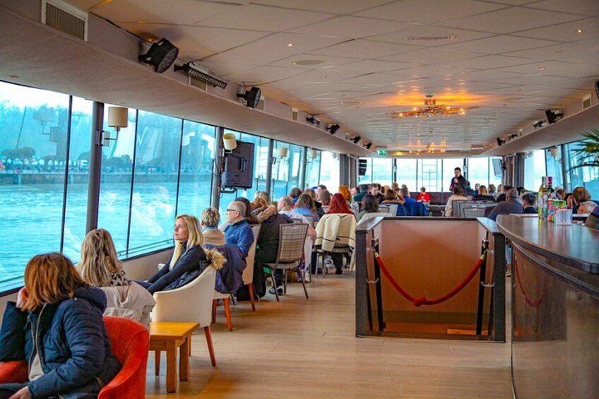 Interior de un crucero con amplios ventanales, suelo de madera y una zona de bar. 3