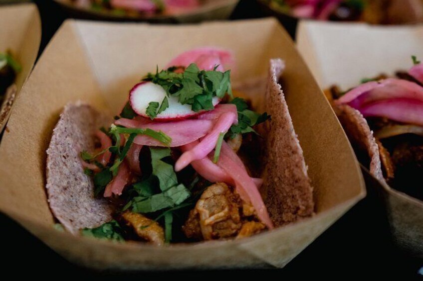 A food item in a paper container with visible ingredients like meat, radish, and herbs. 4