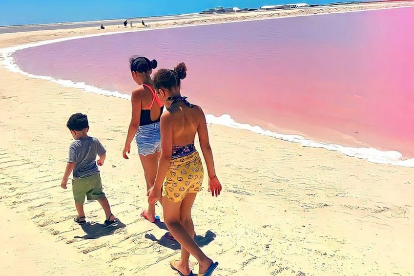 A beach with pink sand and people walking along the shore. 1