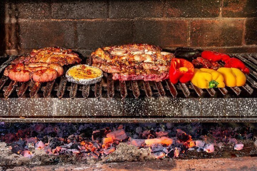A grill with various meats and vegetables being cooked. 1