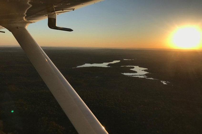 An airplane wing, a sunset, and a landscape with water bodies. 5