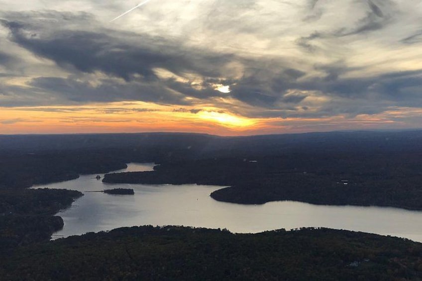 A sunset over a lake surrounded by forested hills. 4