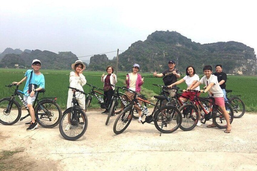 Un grupo de personas con bicicletas en un sendero de tierra, con campos verdes y colinas al fondo. 3