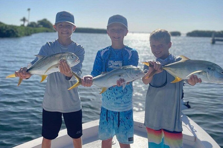 Three people holding fish on a boat. 1