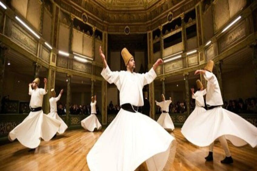 Un gruppo di ballerini in costumi bianchi si esibisce in una maestosa sala con architettura decorata. 2
