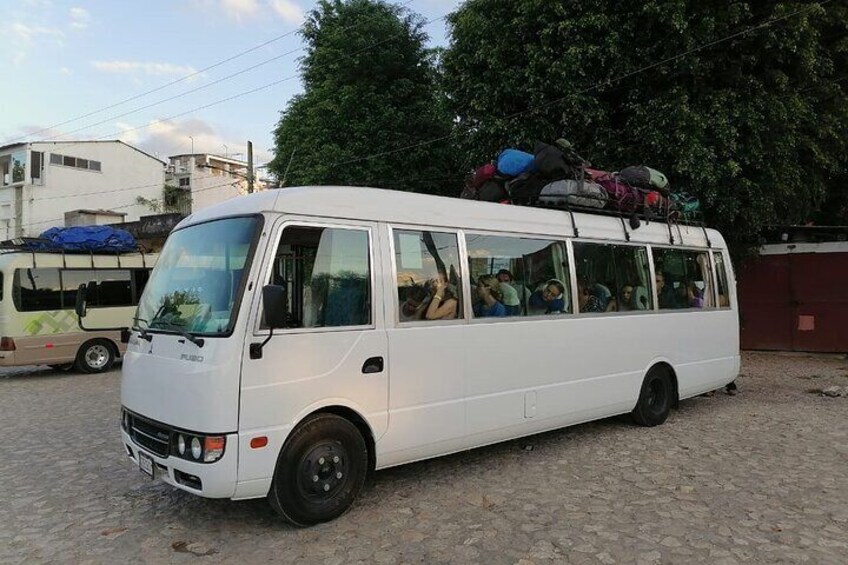 A white van parked on a cobblestone surface with passengers inside. 5