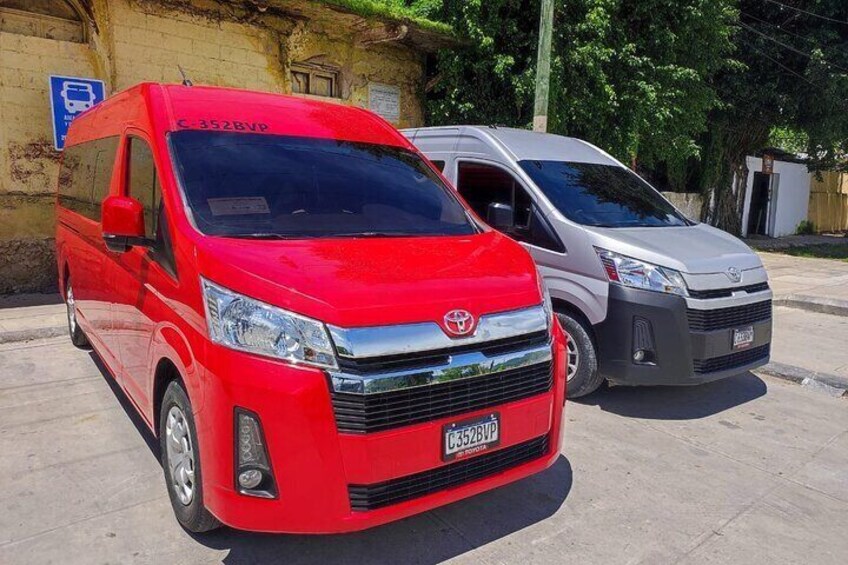 A red and a silver Toyota van parked on a concrete surface with a blue handicapped parking sign in the background. 3