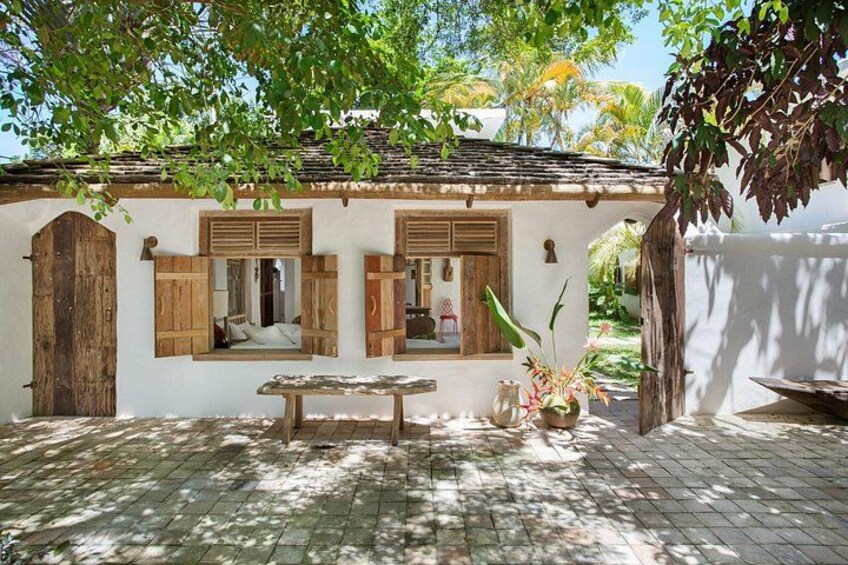 A rustic building with wooden shutters, a bench, and potted plants. 3