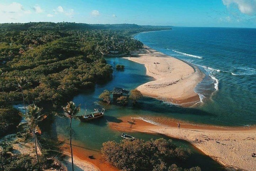 A coastal landscape with a sandy beach, a river, and dense greenery. 2