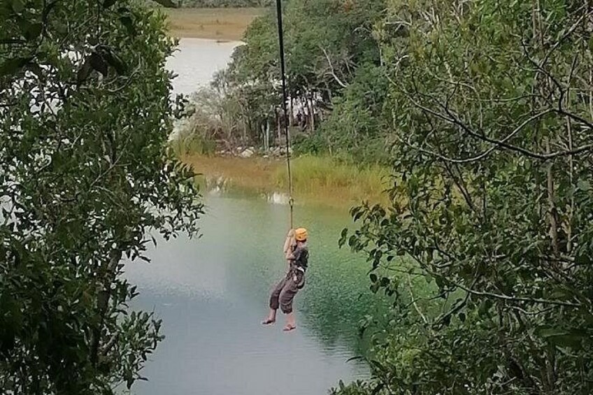 A person swinging on a rope over a body of water surrounded by trees. 3