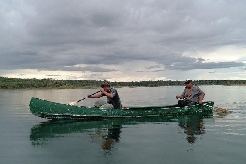 Two people in a green canoe on a calm body of water with a cloudy sky. 4
