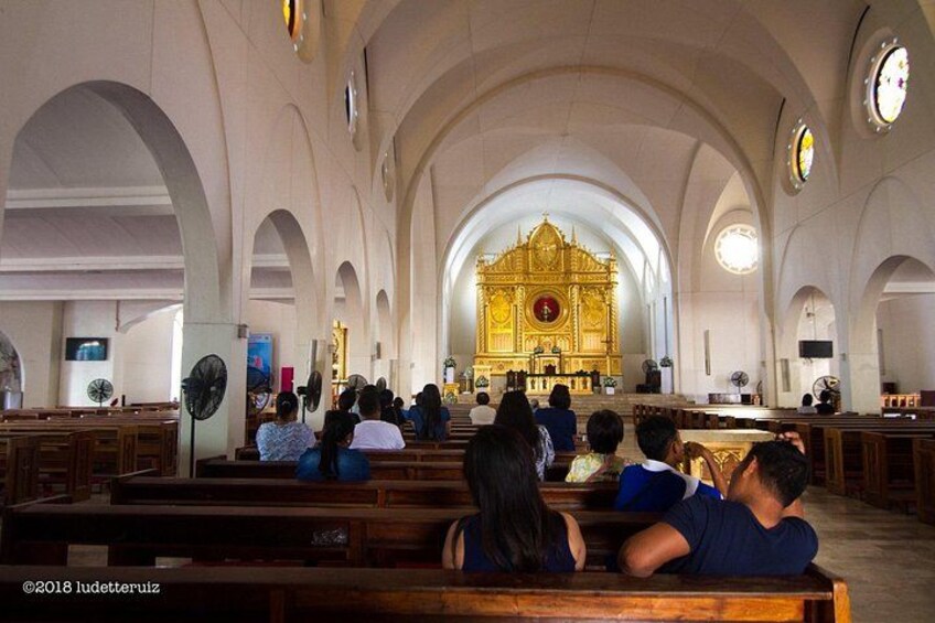 Interior de una iglesia con bancos y un altar central. 2