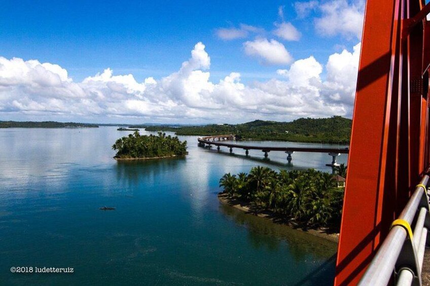 Un lago tranquilo con una pequeña isla, un puente y una estructura roja. 3