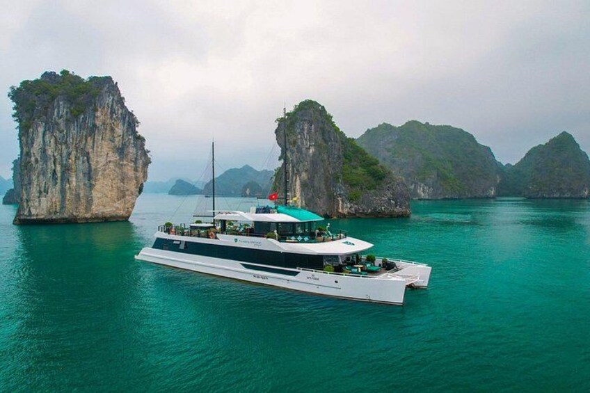 Un barco blanco grande con techo verde navegando en aguas turquesas entre dos islas grandes de piedra caliza. 1