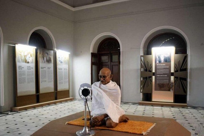 A person seated on a mat in a room with arched ceilings and informational panels. 5